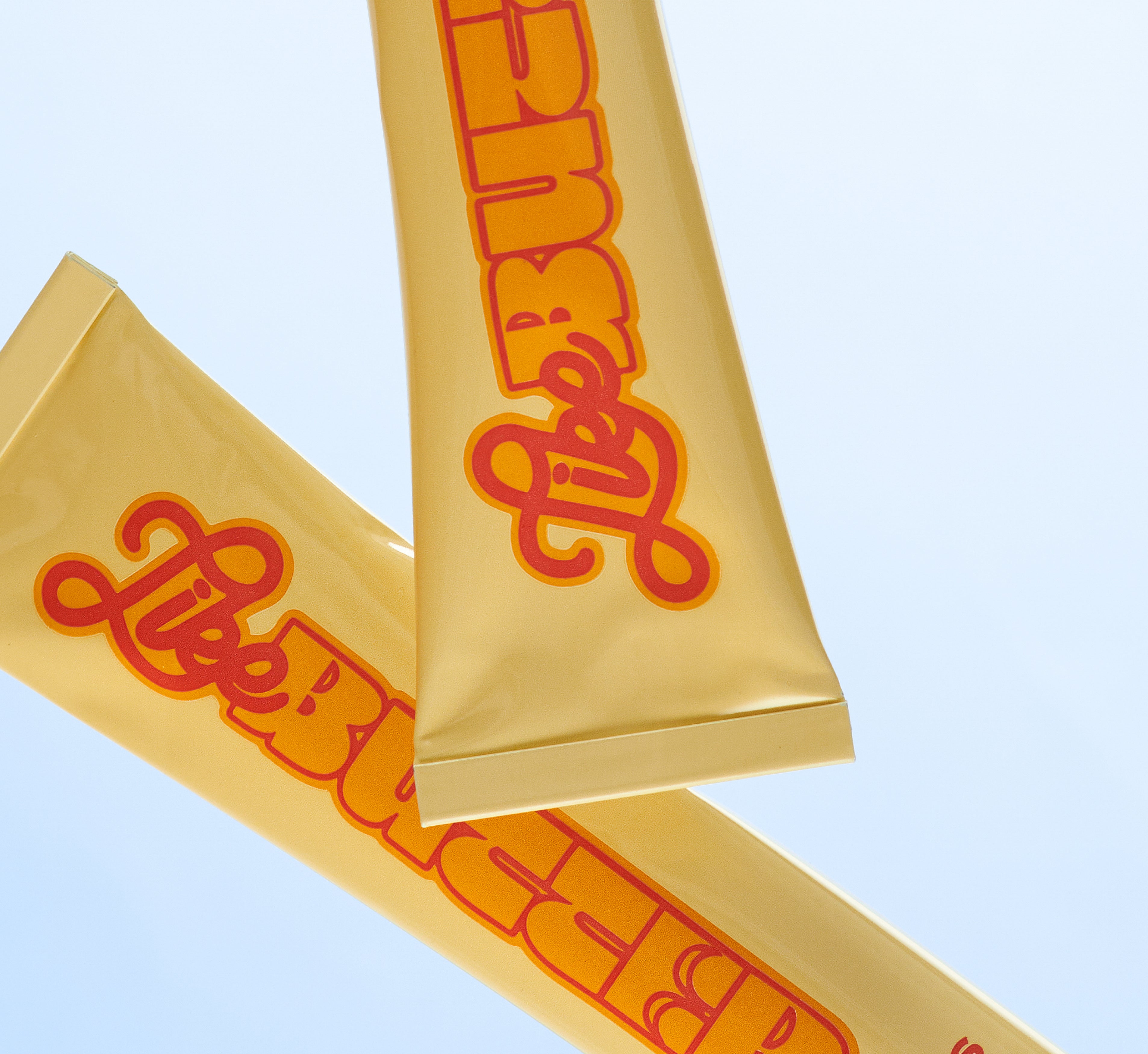 Two squeezed Topicals Like Butter moisturizer tubes crossed against a pale blue background, showing the well-loved hydrating cream packaging.